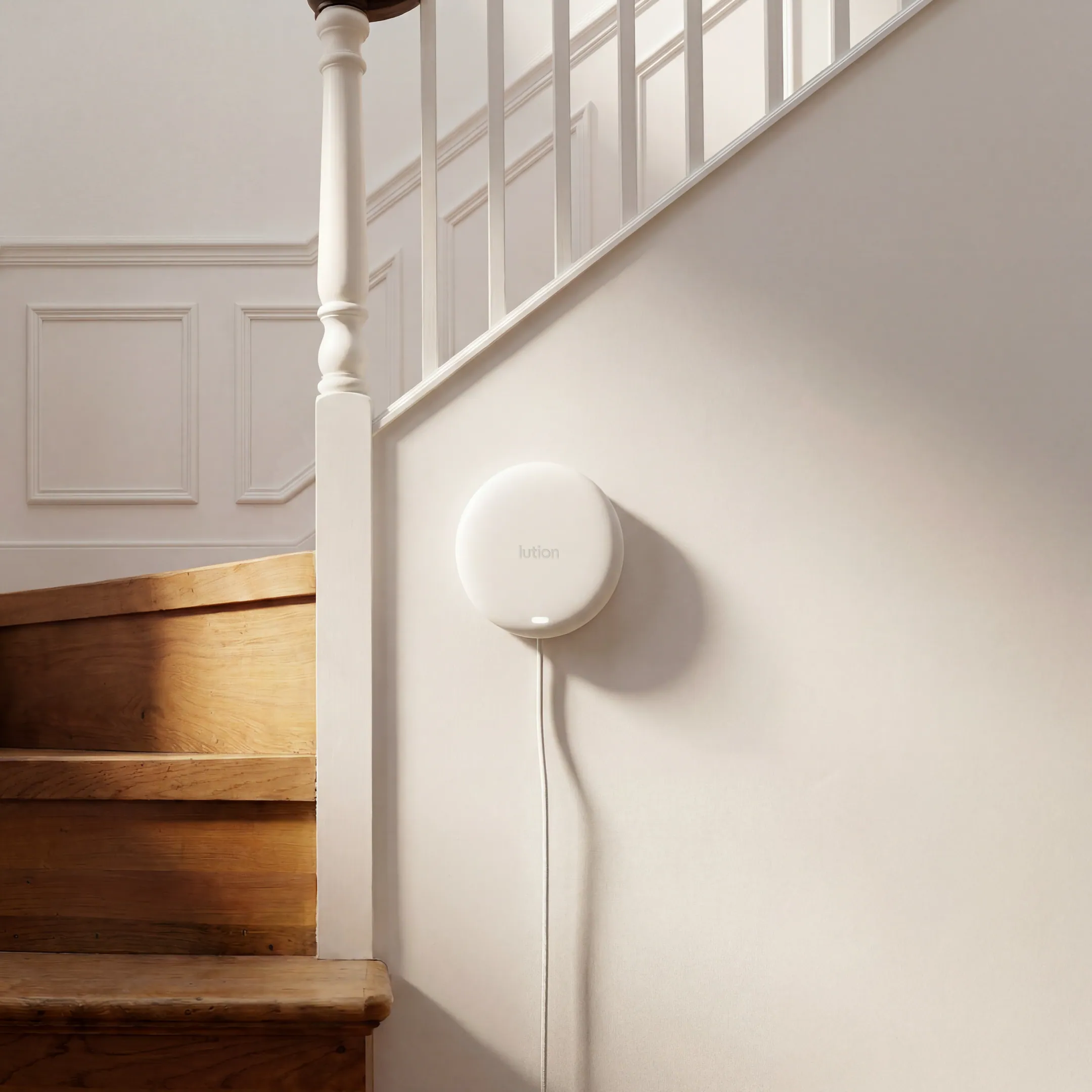 A Lution in-home sensor installed on a wall by a staircase